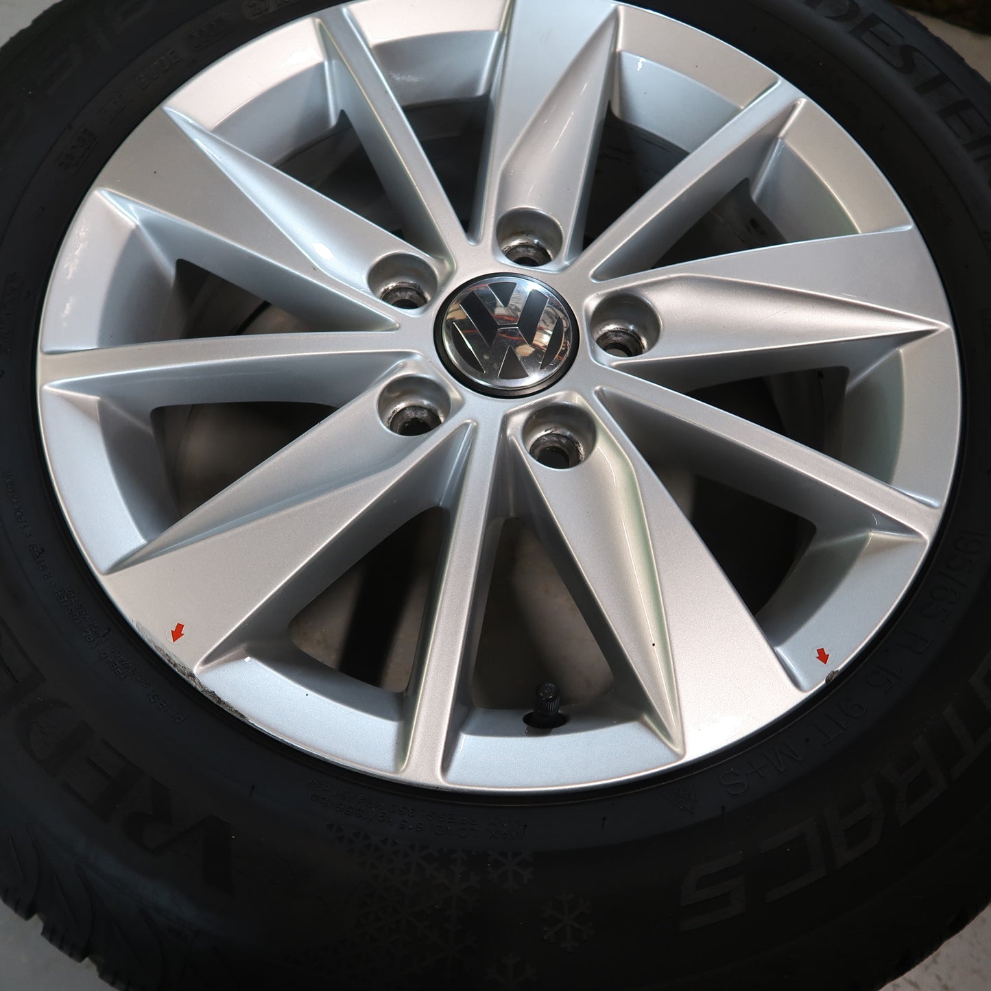 Enkele zilverkleurige lichtmetalen velg met VW-logo en winterband