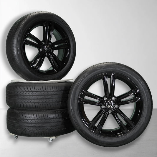 Twee zwarte velgen met zomerbanden, glanzende multi-spokes en Volkswagen-logo