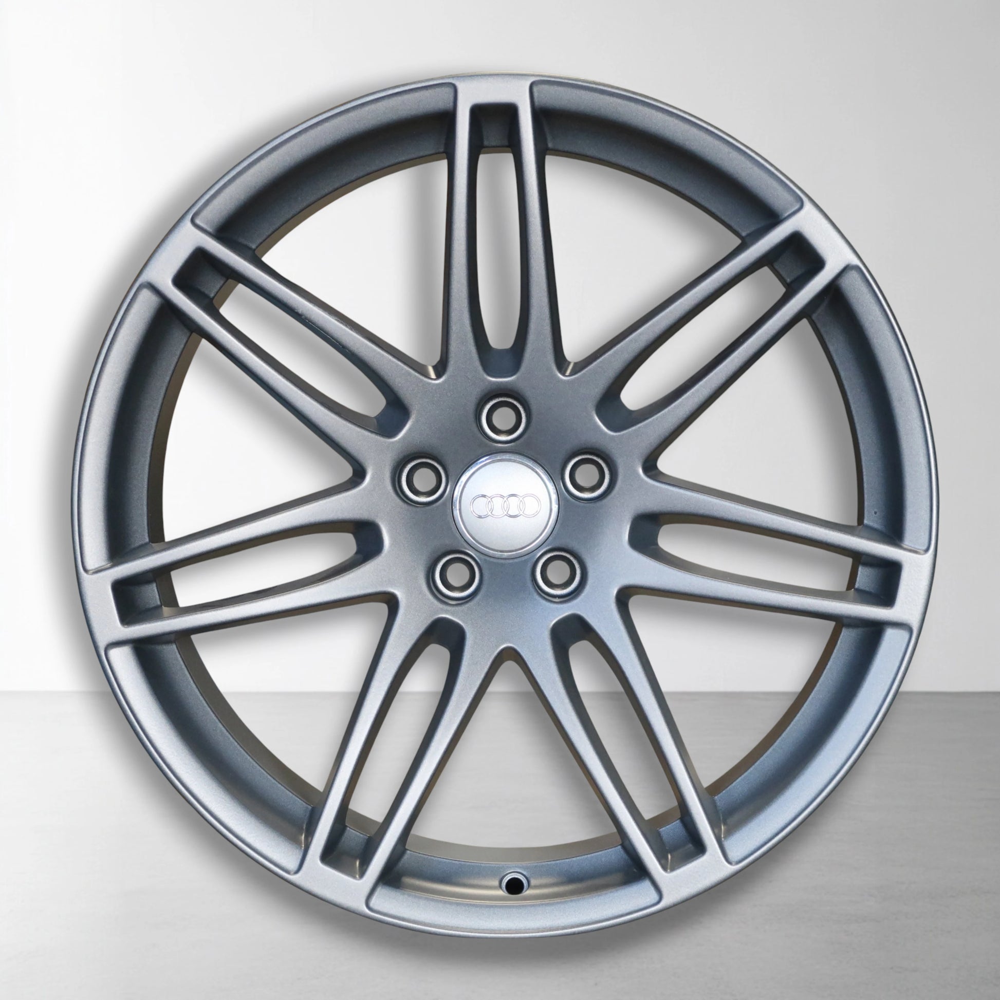 Enkele 20 inch lichtmetalen velg met spaken en ronde naafkap, donkergrijs/zilver.