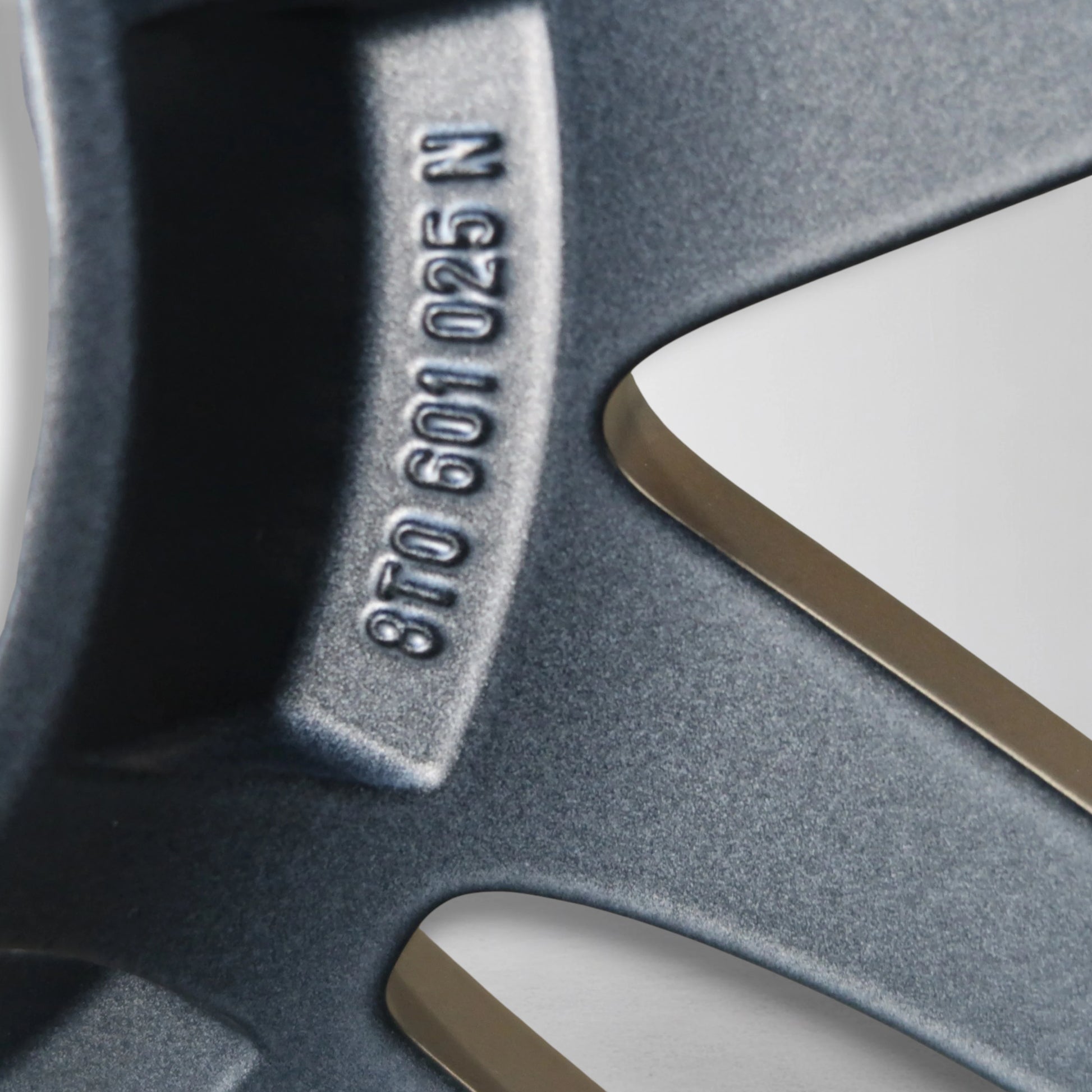 Close-up van gegraveerde velgmarkering op donkergrijze velg, deel van code zichtbaar.