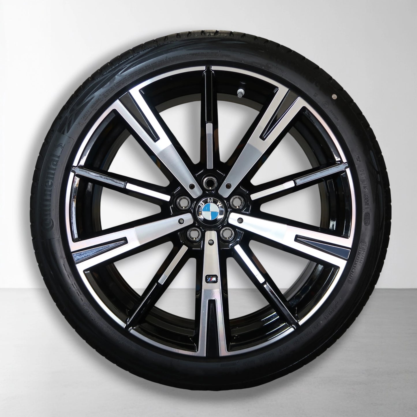 Zwarte 5-spaaks velg met BMW-embleem en zwarte zomerband.