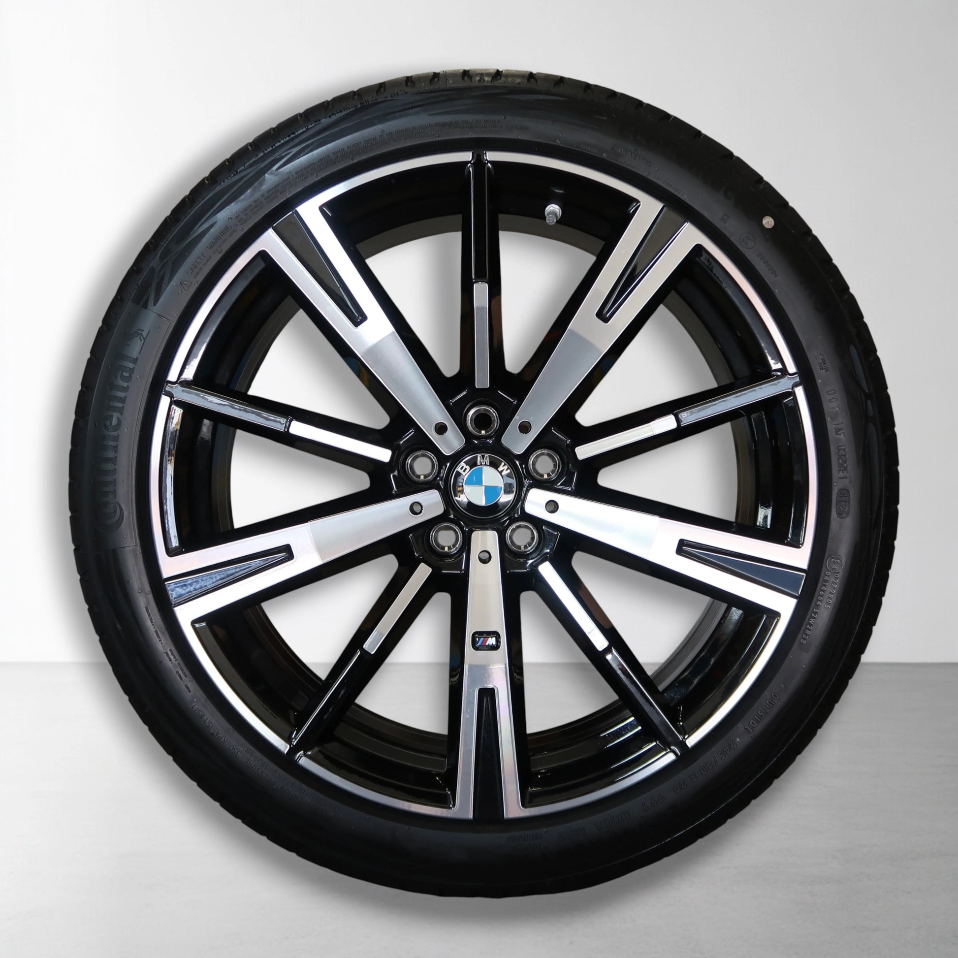 Zwarte 5-spaaks velg met BMW-embleem en zwarte zomerband.