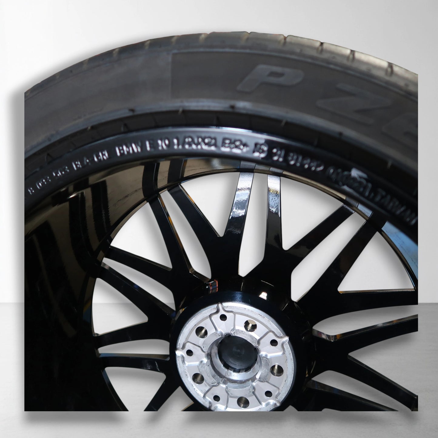 Originele lichtmetalen velg met zomerband, close-up van zwarte en zilveren spaken.