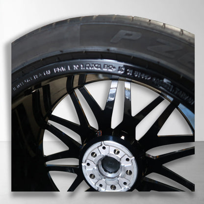 Originele lichtmetalen velg met zomerband, close-up van zwarte en zilveren spaken.