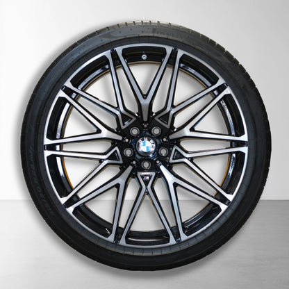 Originele lichtmetalen velg met zomerband, zwarte en zilveren spaken met BMW-logo.