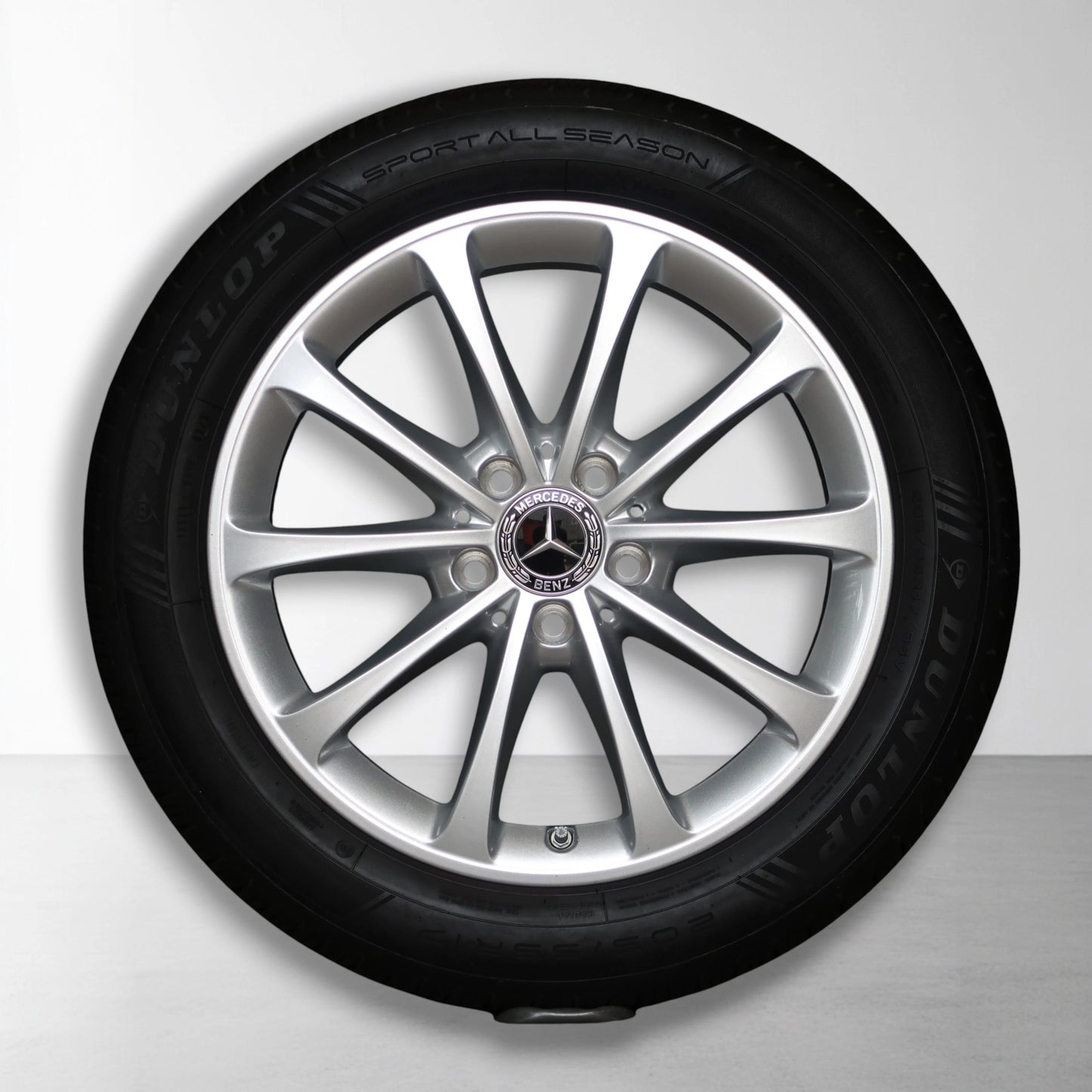 Metalen velg met all-season band, zilverkleurige spaken en Mercedes-logo in naaf