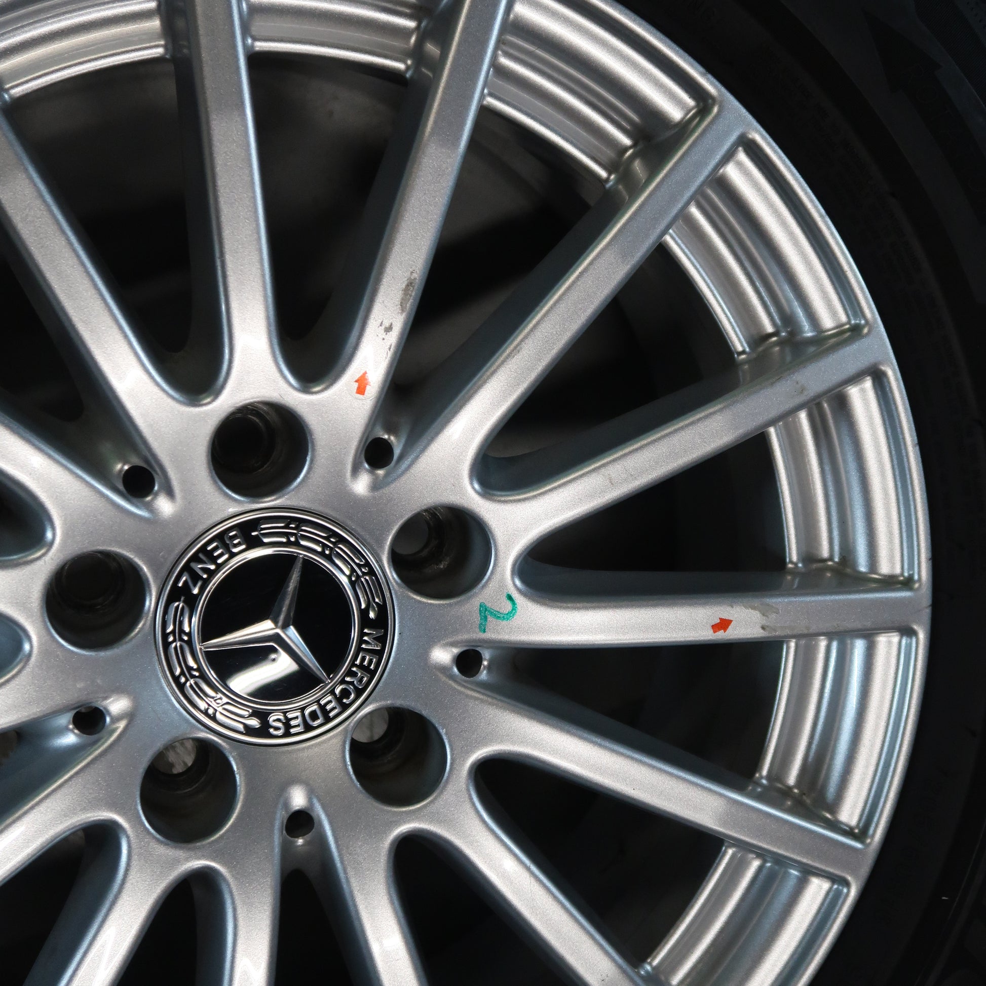 Close-up: Mercedes-velg met zilveren spaken en logo in naafdop