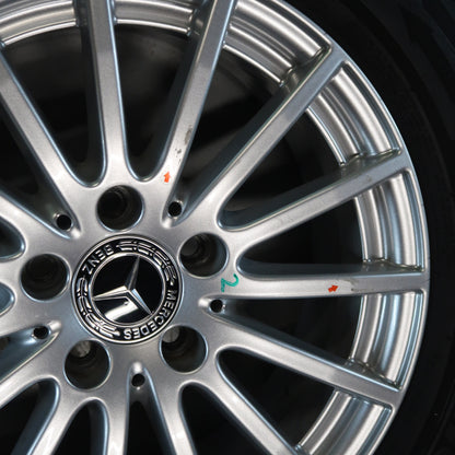 Close-up: Mercedes-velg met zilveren spaken en logo in naafdop