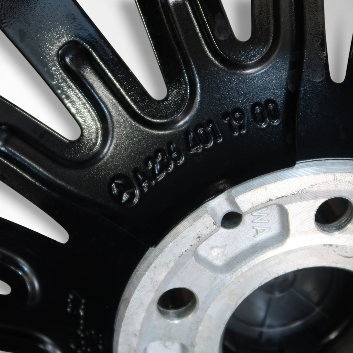 Close-up van zwarte velg met gegraveerde cijfers en boutgaten naast bandvlak
