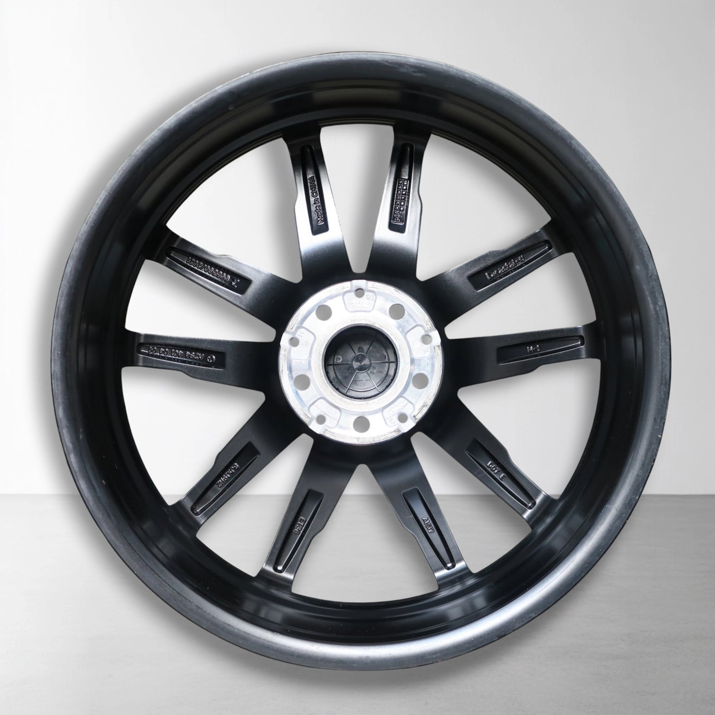 Zwarte 19 inch velg met lichtmetalen spaken en zilveren naafdop, vooraanzicht.