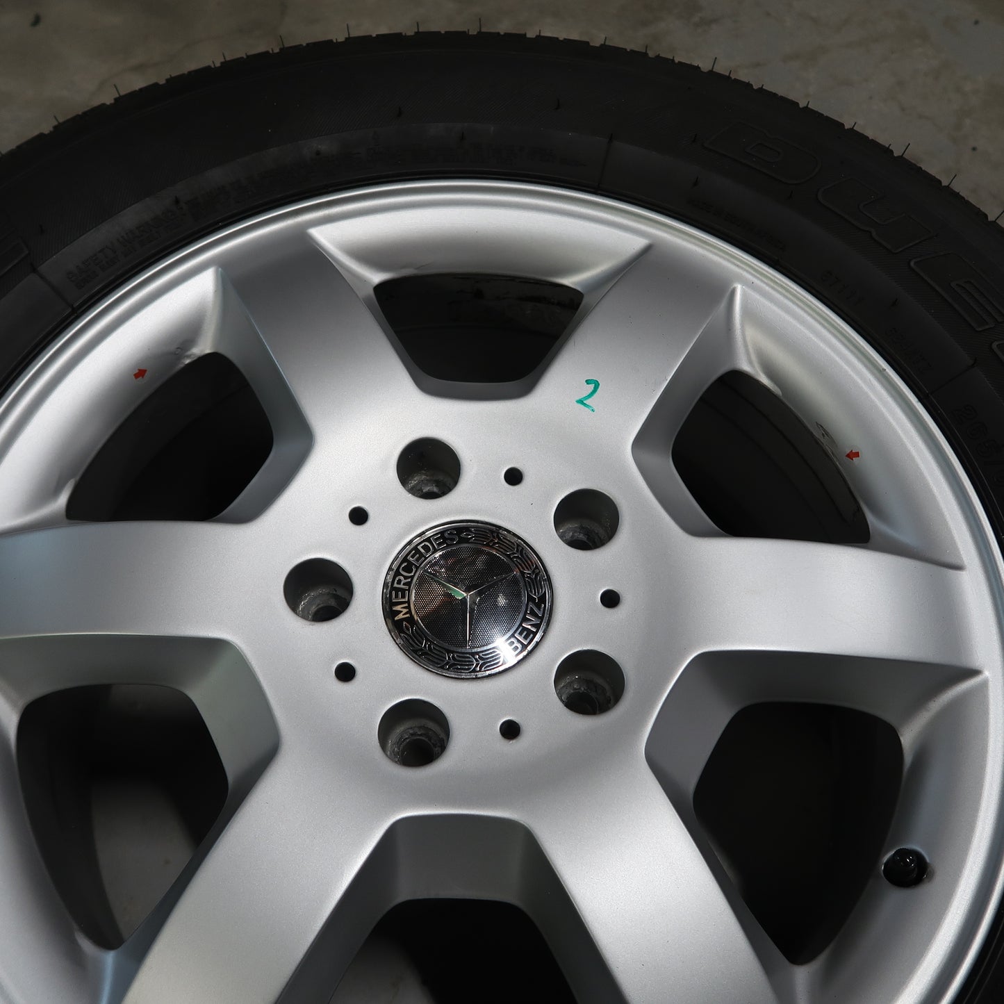Close-up van zilverkleurige velg met naafdop en zwarte bandenrand