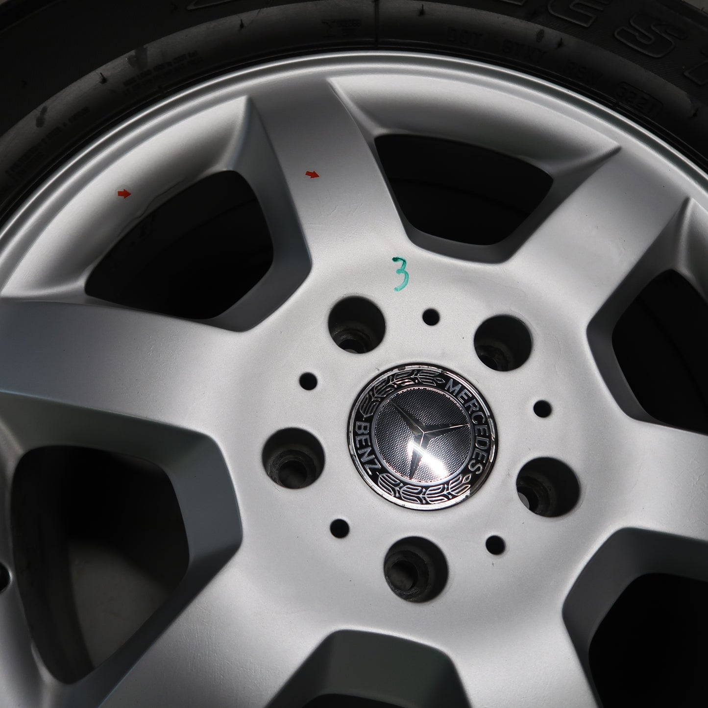 Close-up van zilverkleurige velg met Mercedes-naafdop en zwarte bandprofilering