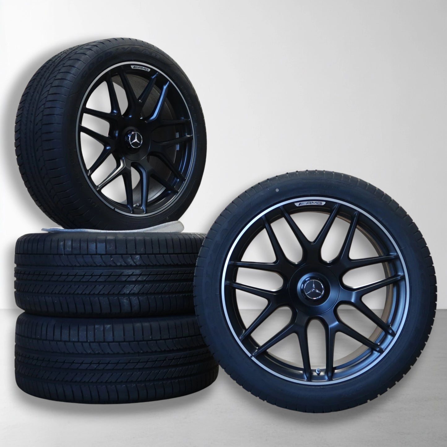 Twee velgen met zomerbanden, zwarte vijfspaks design en Mercedes-bekleding.