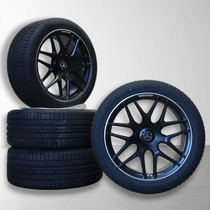 Twee velgen met zomerbanden, zwarte vijfspaks design en Mercedes-bekleding.