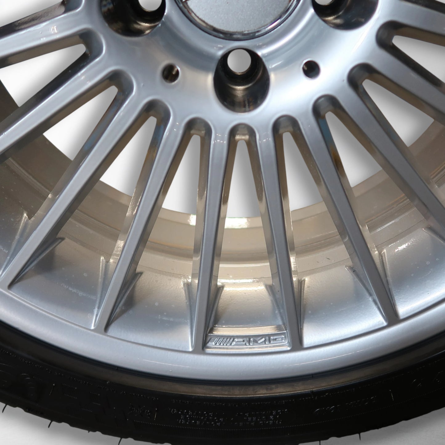 Close-up van zilveren velg met multispaaks en zwarte band