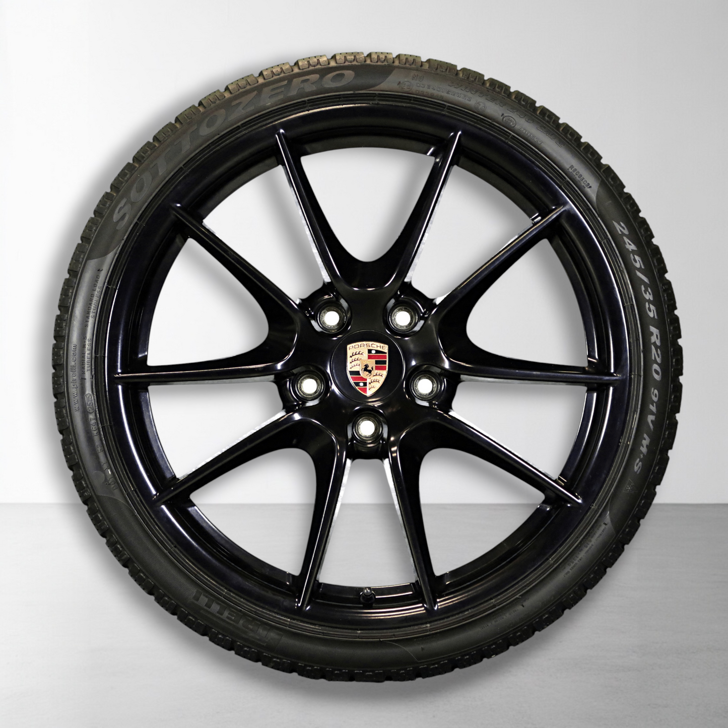 Zwarte velg met Porsche-embleem en winterband, close-up
