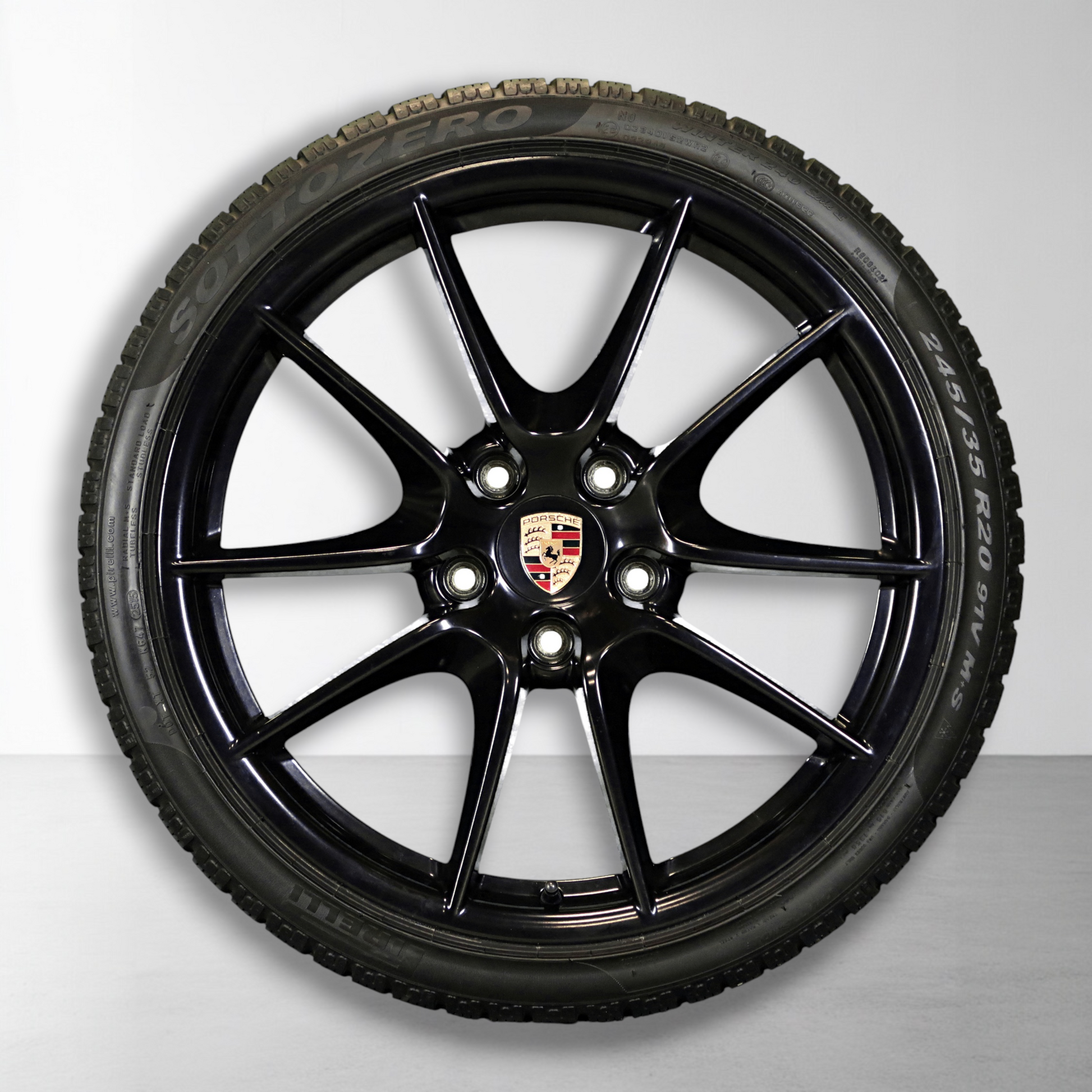 Zwarte velg met Porsche-embleem en winterband, close-up