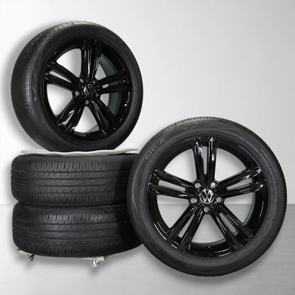Twee zwarte velgen met zomerbanden, glanzende multi-spokes en Volkswagen-logo
