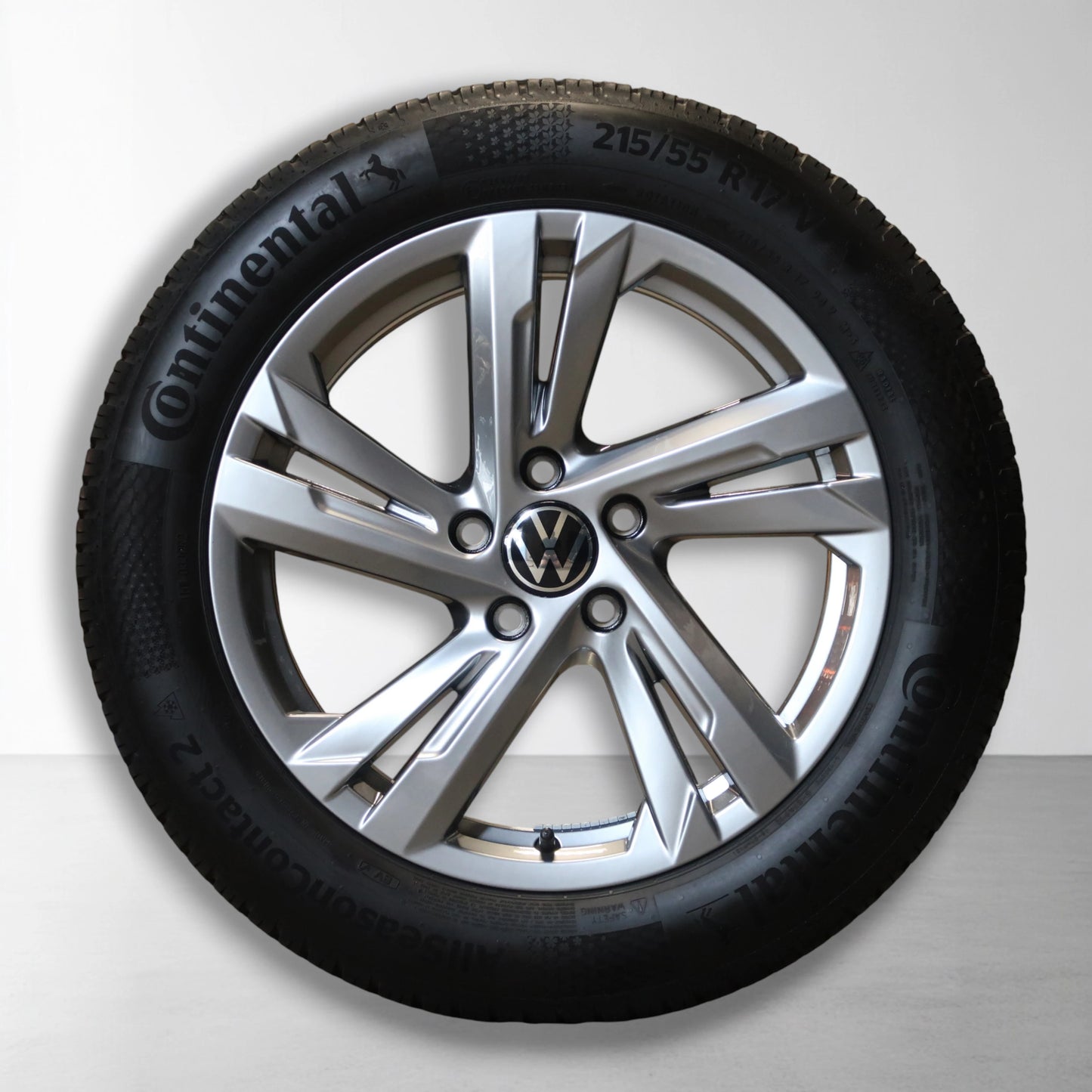 Velg met all-season band; zilveren spaken en Volkswagen-logo in het midden.